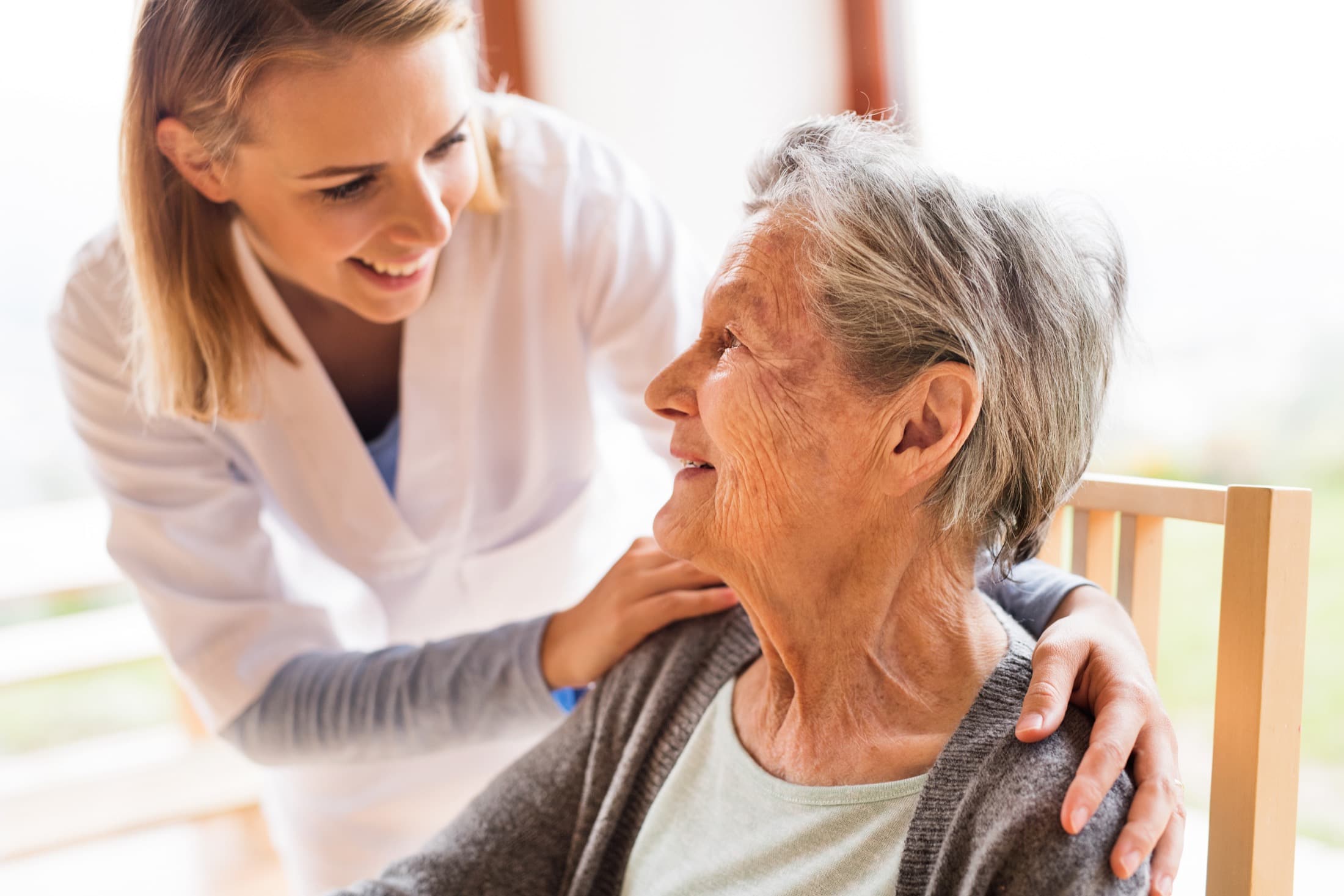 Caregiver speaking warmly with an older adult in a bright home