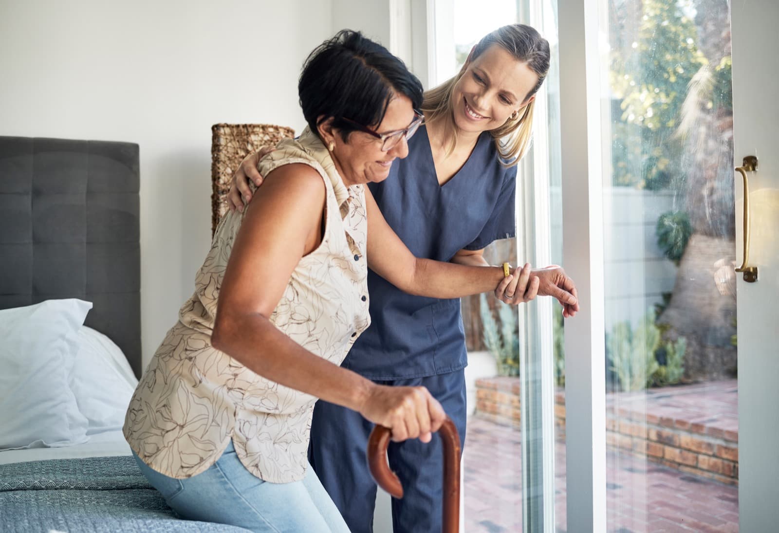 Caregiver gently supporting an older adult with daily movement at home